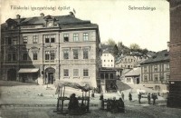 Selmecbánya, Schemnitz, Banska Stiavnica; M. k. Bányászati és Erdészeti Főiskola igazgatósági épület, Ernst Zsigmond üzlete, piaci árusok. Joerges kiadása / mining and forestry college directorate's building, shops, market vendors